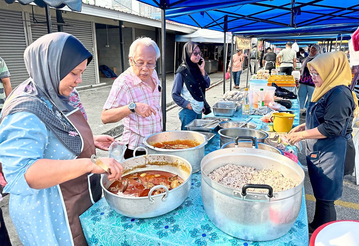 Suhana (left) is hopeful of turning a handsome profit at the Ramadan bazaar with her offering of traditional Kelantan fare.